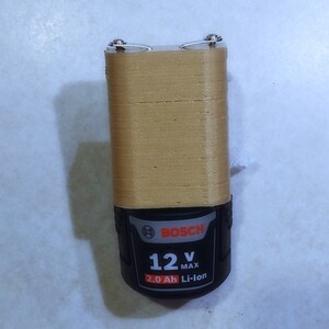 May include: A gold-colored battery for a Bosch power tool. The battery has a black label with the text "Bosch", "12V MAX", and "2.0 Ah Li-Ion".