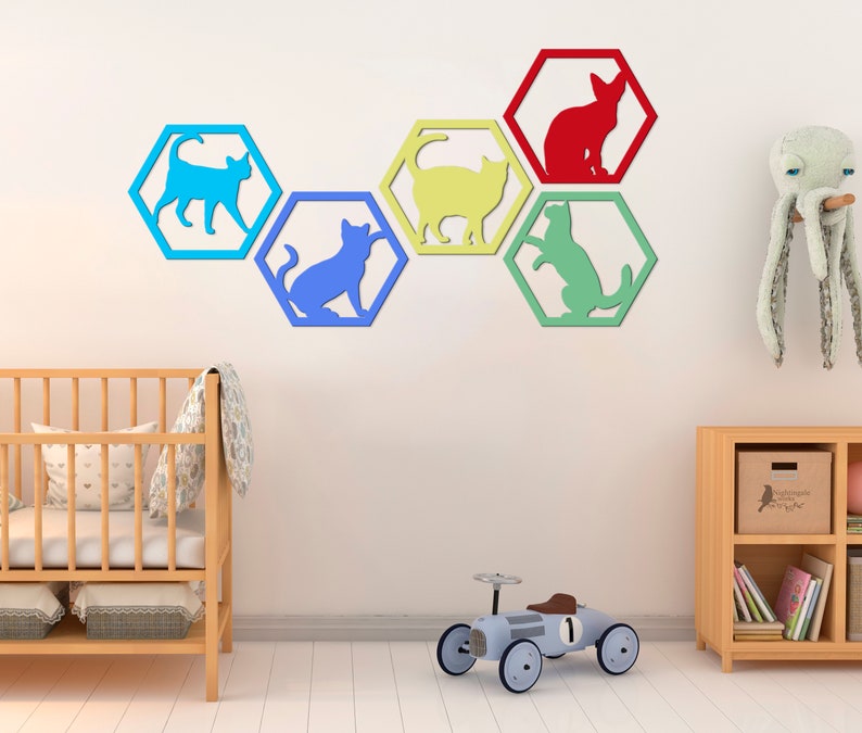 Pode incluir: Um conjunto de seis decora&ccedil;&otilde;es de parede hexagonais coloridas com recortes de silhuetas de gatos em v&aacute;rias poses. Os hex&aacute;gonos est&atilde;o dispostos em uma fila e s&atilde;o pintados em tons de azul, amarelo, verde e vermelho.
