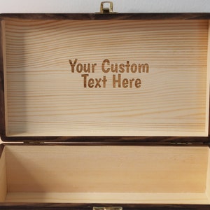 May include: A wooden box with a hinged lid and a brass latch. The inside of the box is lined with wood and has the text "Your Custom Text Here" engraved on the surface.