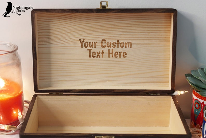 May include: A wooden box with a hinged lid and a brass latch. The inside of the box is lined with wood and has the text "Your Custom Text Here" engraved on the surface.