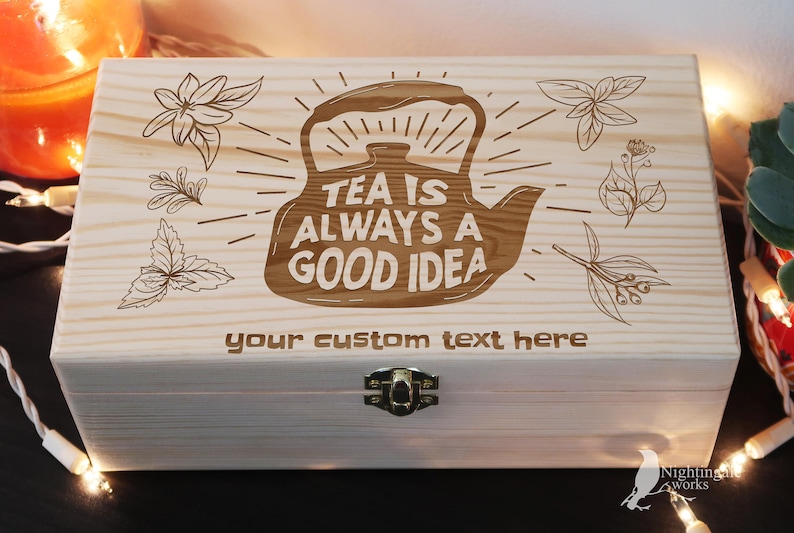 May include: A wooden tea box with a light wood finish. The lid is engraved with a teapot and the text "Tea is always a good idea". The box also has a space for a custom text inscription.