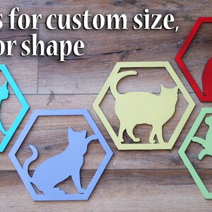 Pode incluir: Cinco recortes de gatos de madeira hexagonais em diferentes cores. As cores s&atilde;o turquesa, lavanda, amarelo, verde e vermelho. O texto "Text us for custom size, color or shape" est&aacute; na parte superior da imagem.