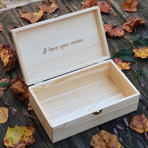 May include: A wooden box with a hinged lid, open to reveal an empty interior. The lid is engraved with the words "I love you more".