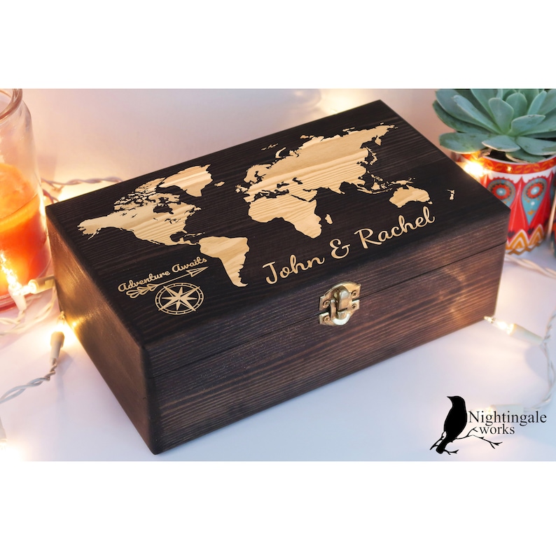 May include: A dark wooden box with a world map design engraved on the lid. The box has a brass latch and is personalized with the names "John & Rachel" and the text "Adventure Awaits".