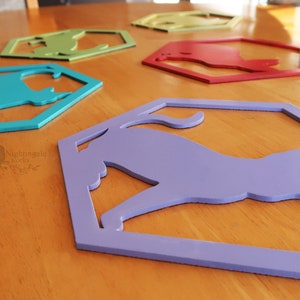 Pode incluir: Cinco pe&ccedil;as de decora&ccedil;&atilde;o de parede de madeira em forma de hex&aacute;gono com uma silhueta de gato recortada. Os hex&aacute;gonos s&atilde;o pintados em diferentes cores: azul-esverdeado, verde, amarelo, vermelho e roxo.