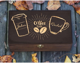 May include: A dark brown wooden box with a hinged lid and a brass latch. The box is engraved with two coffee cups, one with the name "John" and the other with the name "Rachel". The text "coffee time" is also engraved on the box.