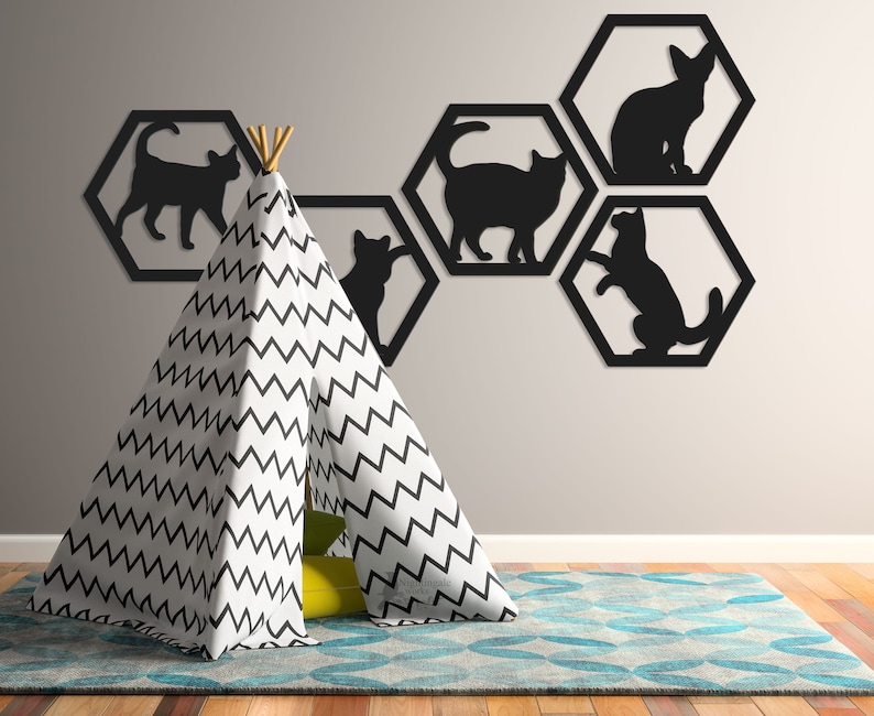 Pode incluir: Silhuetas de gatos pretos em molduras hexagonais numa parede cinza claro, com uma tenda tipi com padr&atilde;o de chevron preto e branco em primeiro plano.