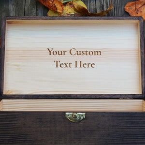 May include: A wooden box with a hinged lid, open to reveal a light wood interior. The inside of the lid is engraved with the text "Your Custom Text Here".