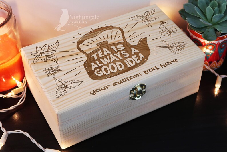 May include: A wooden tea box with a hinged lid and a brass latch. The box is engraved with a teapot and the text "Tea is always a good idea". The box also has space for a custom text message.