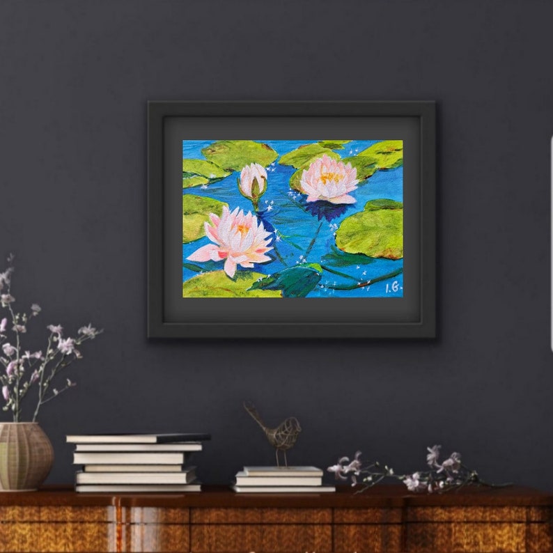 May include: A framed painting of pink water lilies on a blue background with green lily pads. The painting is signed "I.G."