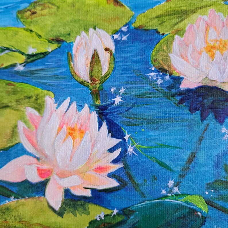 May include: A painting depicting white water lilies with pink edges, blossoming in a pond with blue water. The water lilies are surrounded by green lily pads and the water is sparkling with light.