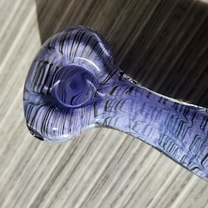 Pode incluir: Um cachimbo de vidro roxo com um design de espiral. O cachimbo tem uma tigela e um bocal.
