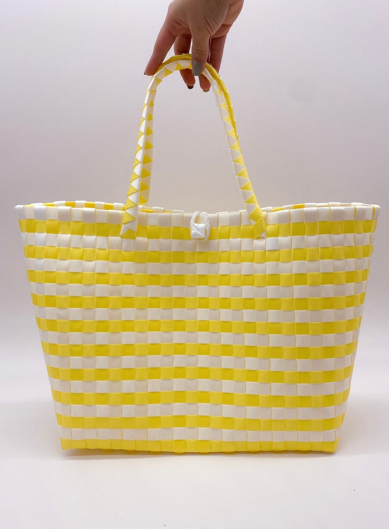 May include: Yellow and white striped woven tote bag with a white handle.