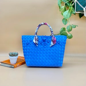May include: A blue woven tote bag with a patterned fabric handle. The bag has a woven design and is made of a sturdy material.