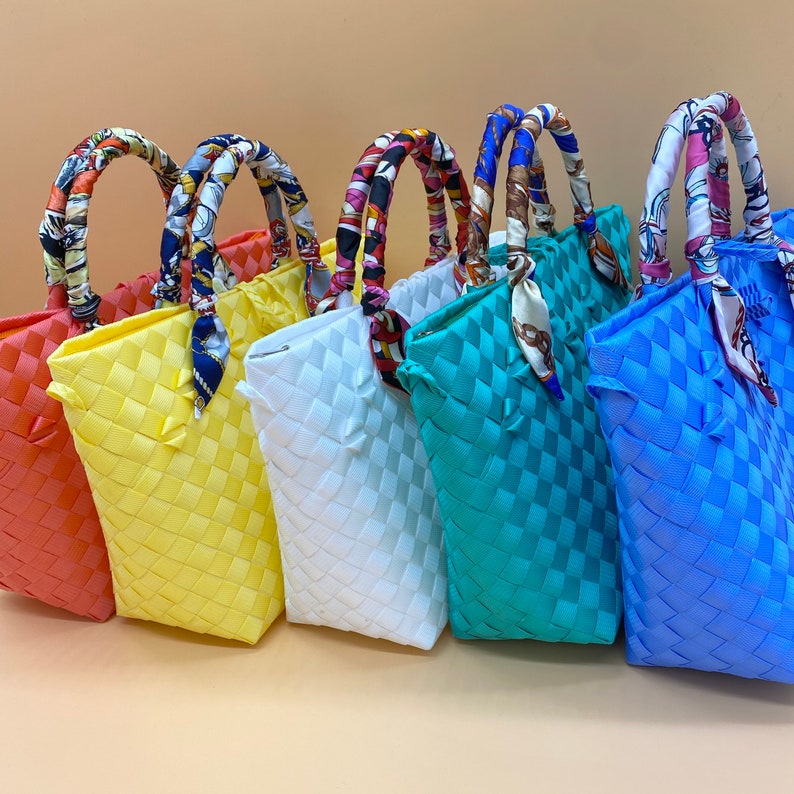 May include: Five woven tote bags in different colors, including coral, yellow, white, turquoise, and blue. Each bag has a unique patterned fabric handle.