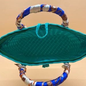 May include: A turquoise woven tote bag with a blue and white patterned fabric handle. The bag is open and the inside is visible.