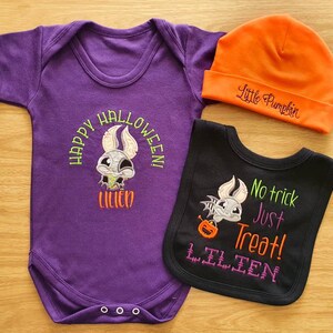 May include: A Halloween-themed baby outfit set featuring a purple onesie with "Happy Halloween!" and a bat design, an orange beanie with "Little Pumpkin", and a black bib with "No trick Just Treat!" and a bat design.