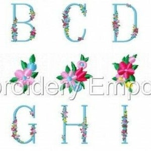 May include: A collection of embroidered letters A through J, each in a light blue color and adorned with colorful floral designs. The letters are displayed in two rows, with the text "Embroidery Emporium" in the center.