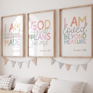 Puede incluir: Tres impresiones artísticas enmarcadas con citas inspiradoras en colores pastel. Las impresiones, en marcos de madera, dicen "I AM fearfully and wonderfully made", "GOD has great PLANS for me" y "I AM loved BEYOND MEASURE". Una guirnalda de pequeñas banderas cuelga debajo.