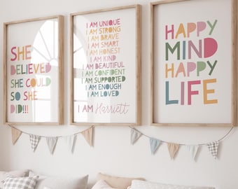 May include: Three framed wall art prints with inspirational quotes in colorful text. The prints are in a child's room, above a wooden storage bench with white bins and decorative pillows. A banner of small flags hangs above the prints.