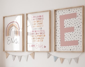 May include: Three framed prints with a pink and white color scheme. The first print features a rainbow with the name "Erin" underneath. The second print has the name "Erin" with a heart and a list of positive affirmations. The third print features a large pink letter "E" with white polka dots.