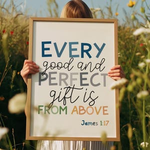 May include: A framed sign with the text "EVERY good and PERFECT gift is FROM ABOVE James 1:17". The text is in various colours, including blue, grey, and green, against a white background. The frame is a light brown colour.