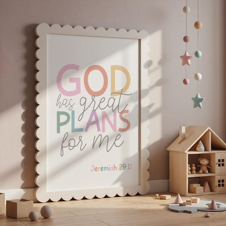 以下が含まれることがあります： パステルカラーで「GOD has great PLANS for me」と書かれた額入りのプリント。フレームはスカラップエッジです。保育園の環境で壁に立てかけられたプリントで、木製のおもちゃと背景にモビールがあります。