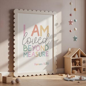 以下が含まれることがあります： パステルカラーで「I AM loved BEYOND MEASURE」の文字が書かれた、スカラップエッジのフレーム入りプリント。聖書のローマ人への手紙8:38が下にあります。木製のおもちゃとモービルがある子供部屋に飾られています。