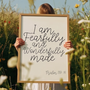 Op de afbeelding: Een ingelijst bord met de tekst "I am Fearfully and Wonderfully made" in zwart schrift. Het bord bevat ook de tekst "Psalm 139:14" in een kleiner lettertype. De lijst is lichtbruin.