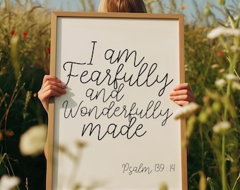 May include: A framed sign with the text "I am Fearfully and Wonderfully made" in black script. The sign also includes the text "Psalm 139:14" in a smaller font. The frame is a light brown color.