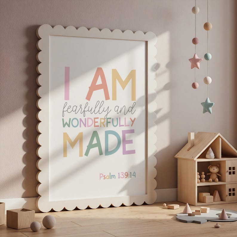 以下が含まれることがあります： パステルカラーで「I AM fearfully and wonderfully made」と書かれた、スカラップエッジのフレーム入りプリント。詩篇139:14の詩が下にあります。プリントは子供部屋の壁に立てかけられています。
