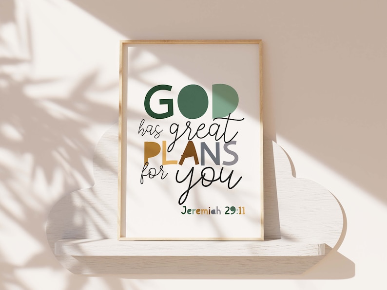 May include: A framed print with a white background and the text "GOD has great PLANS for you Jeremiah 29:11" in colorful letters. The frame is wood with a light brown finish.