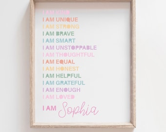 Puede incluir: Una impresión enmarcada con fondo blanco y una lista de afirmaciones positivas en colores arcoíris. El texto dice "Soy amable, soy único, soy fuerte, soy valiente, soy inteligente, soy imparable, soy considerado, soy igual, soy honesto, soy servicial, soy agradecido, soy suficiente, soy amado." El nombre "Sophia" está escrito en rosa en la parte inferior.