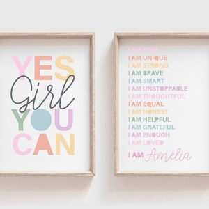 May include: Two framed prints with inspirational quotes. One says "YES Girl YOU CAN" in colorful letters. The other lists positive affirmations like "I AM STRONG" and "I AM BRAVE", with the name "Amelia" at the bottom.