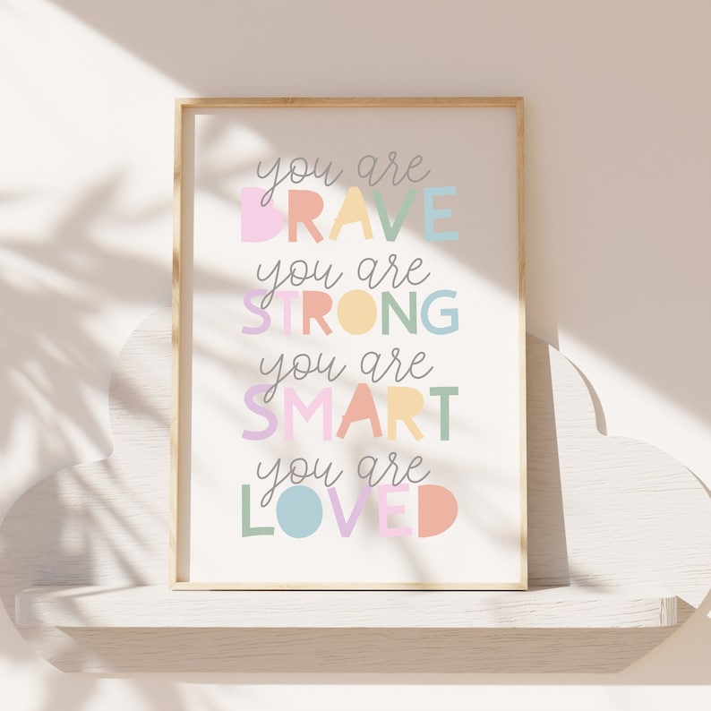 Pu&ograve; includere: Una stampa incorniciata con il testo "You are brave, you are strong, you are smart, you are loved" in lettere colorate su uno sfondo bianco.
