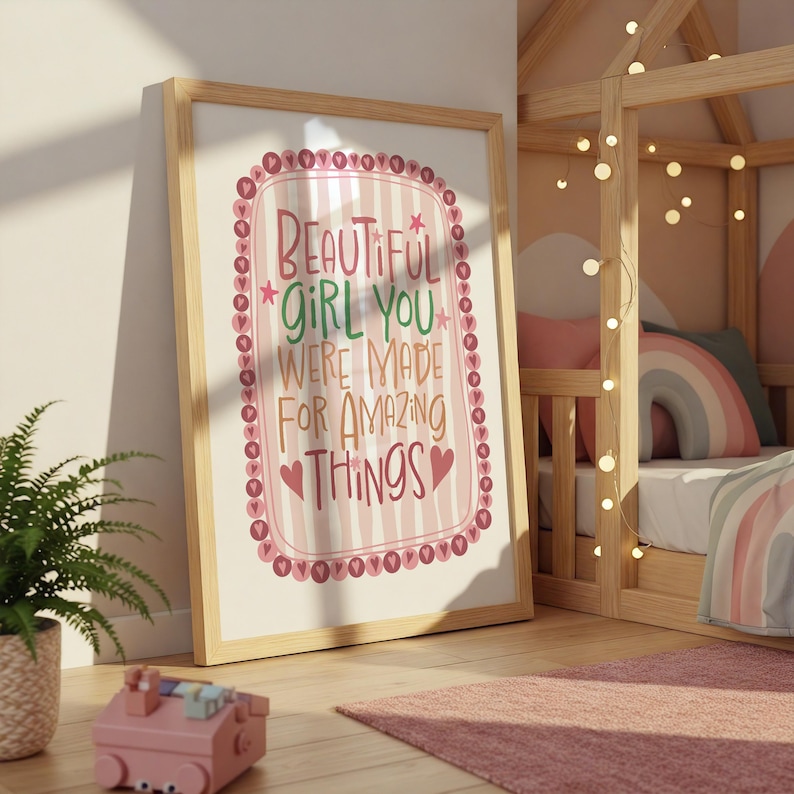 Może przedstawiać: Oprawiony wydruk z napisem "BEAUTIFUL GIRL YOU WERE MADE FOR AMAZING THINGS" w r&oacute;żowo-czerwonym wzorze. Wydruk jest w jasnej drewnianej ramie i opiera się o ścianę w pokoju dziecięcym.