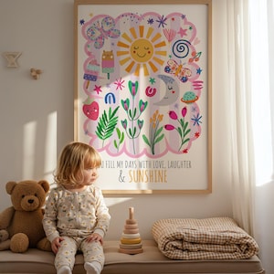 May include: A framed art print with a colorful illustration featuring a smiling sun, butterflies, and flowers. The text reads "YOU FILL MY DAYS WITH LOVE, LAUGHTER & SUNSHINE." A child in a floral onesie sits on a bench with a teddy bear and wooden stacking toy.