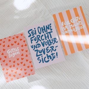 Könnte beinhalten: Drei farbenfrohe Karten mit inspirierenden Zitaten. Eine Karte ist rosa mit roten Herzen und dem Text "Gottes Segen". Eine andere ist helllila mit blauem Text. Die dritte Karte hat orange und weiße Streifen mit weißem Text.