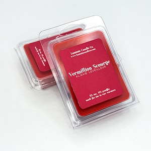 May include: A red wax melt in a clear plastic container. The wax melt is labeled "Vermillion Scourge" with the text "31% soy, 19% pamfin made for use in wax warmers".