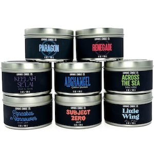 May include: An assortment of Luminis Candle Co. candles in silver tins. Each candle has a black label with a unique name in various colors, such as "Paragon," "Renegade," and "Subject Zero." Each candle is 6 oz / 170 g.