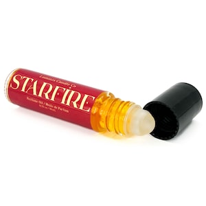 May include: A red and gold perfume oil roller bottle with the word "STARFIRE" in gold lettering. The bottle is open, revealing a clear rollerball applicator and a black cap. The label also reads "Perfume Oil / Huile de Parfum 0.33 fl oz / 10 ml."
