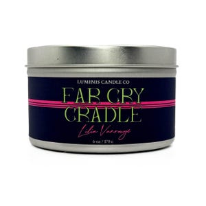 Peut inclure: Une bougie en m&eacute;tal argent&eacute; avec une &eacute;tiquette bleu marine. L'&eacute;tiquette pr&eacute;sente le texte "FAR CRY CRADLE" en vert et rose, avec "Luminis Candle Co" au-dessus et "Lilia Vansrouge" en dessous. La bougie p&egrave;se 170 g.