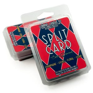 May include: Two packs of Split Card wax melts in clear plastic packaging. The cards have a red and navy diamond pattern with the text "SPLIT CARD" and "Champagne - Lychee - Floral - Cedar". The packaging also includes the brand name and website.