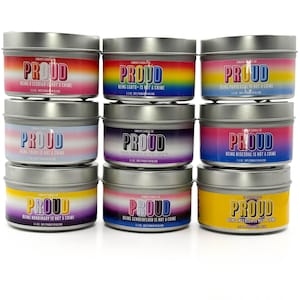 Peut inclure: Neuf bougies en métal avec le mot "PROUD" en grandes lettres. Chaque bougie a un design et un texte différents sur le thème de l'arc-en-ciel, notamment "Être lesbienne n'est pas un crime" et "Être trans n'est pas un crime."