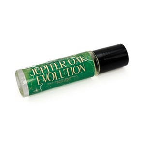 May include: A roll-on perfume oil bottle with a black cap and a green label. The label reads "Jupiter Oak Evolution" in white text. The bottle contains a clear liquid and is set against a white background.