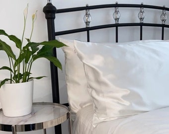 May include: Two white satin pillowcases on a black metal bed frame with crystal accents. The bed frame has a curved headboard.