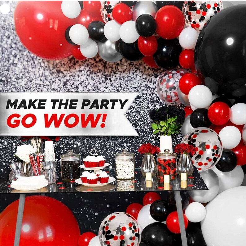 May include: A party decoration set with red, black, white, and silver balloons. The balloons are arranged in a garland shape and include confetti balloons. The text "MAKE THE PARTY GO WOW!" is on a banner in the background.