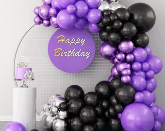 May include: Purple, black and silver balloons arranged in an arch with a "Happy Birthday" sign in the centre. The balloons are arranged in a circular shape and are tied together with string.