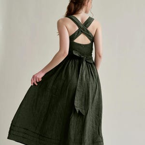 a woman wearing a green dress with a cross back