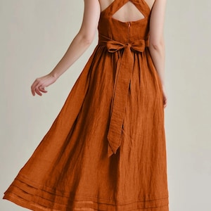 a woman in an orange dress with a cross back